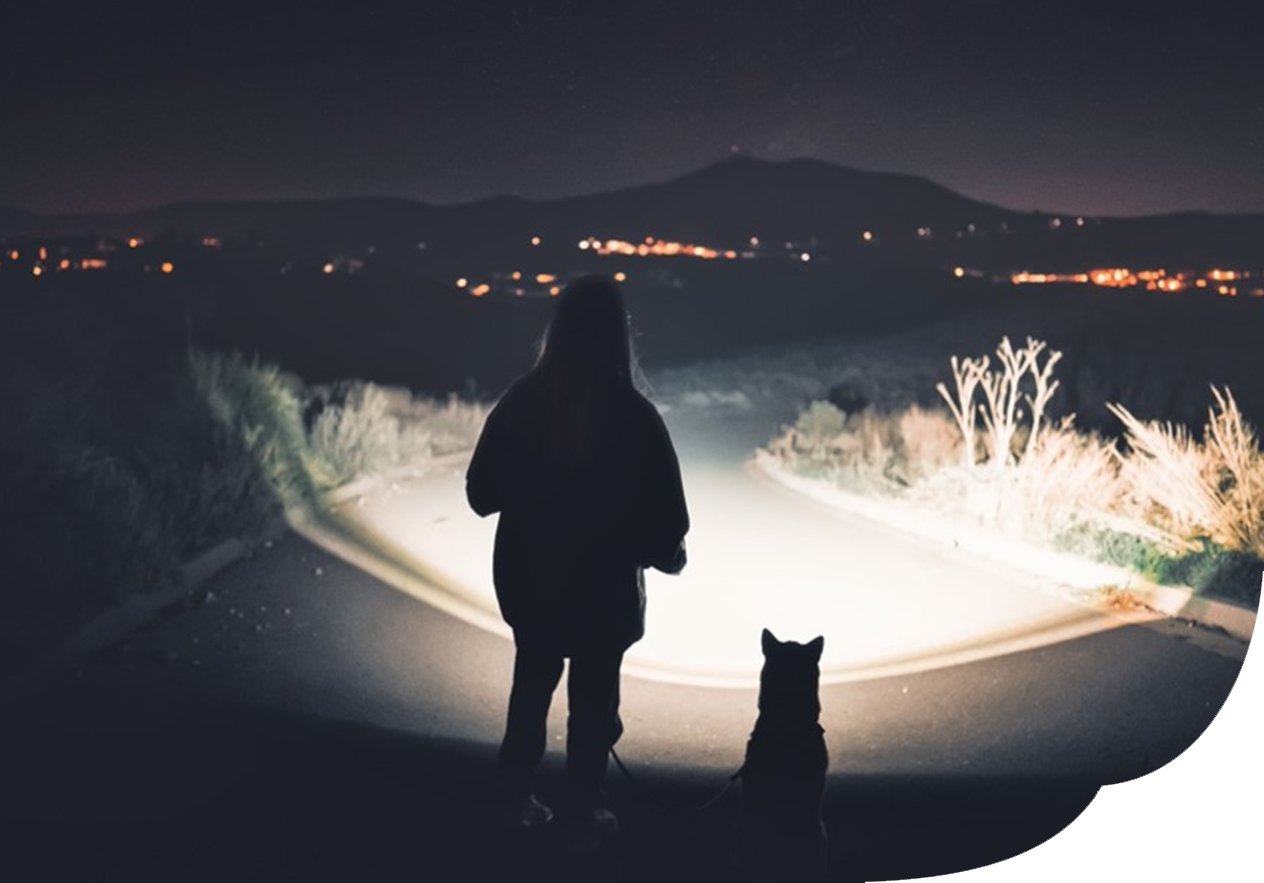 Frau mit Hund im Dunkeln und Taschenlampe